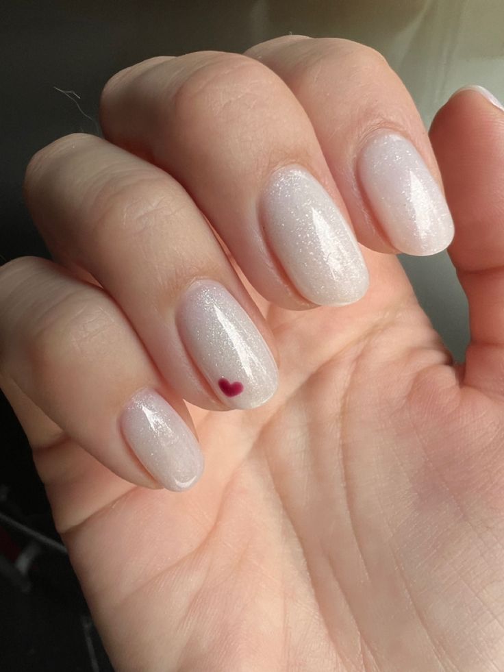 Sophisticated Nail Design with Subtle Shimmer and Charming Heart Accent