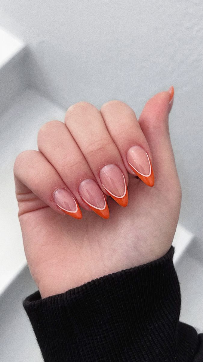 Chic Almond-Shaped Nails with Vibrant Orange Tips and Modern White Accents