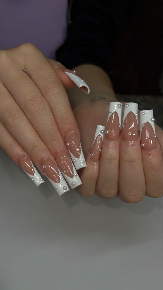 Chic Nude and White Tip Nail Design with Glossy Finish and Elegant Embellishments.