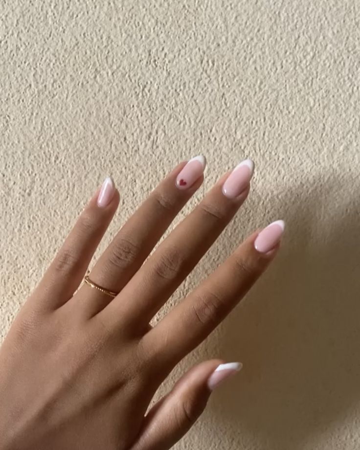 Chic Soft Pink French Tip Nails with Playful Red Heart Accent and Minimalist Gold Ring.