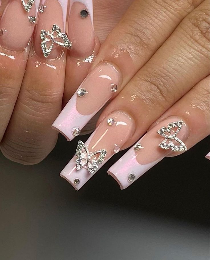 Chic Elegant Nail Design: Nude Base with Pink Tips, Rhinestones, and Butterfly Embellishments.