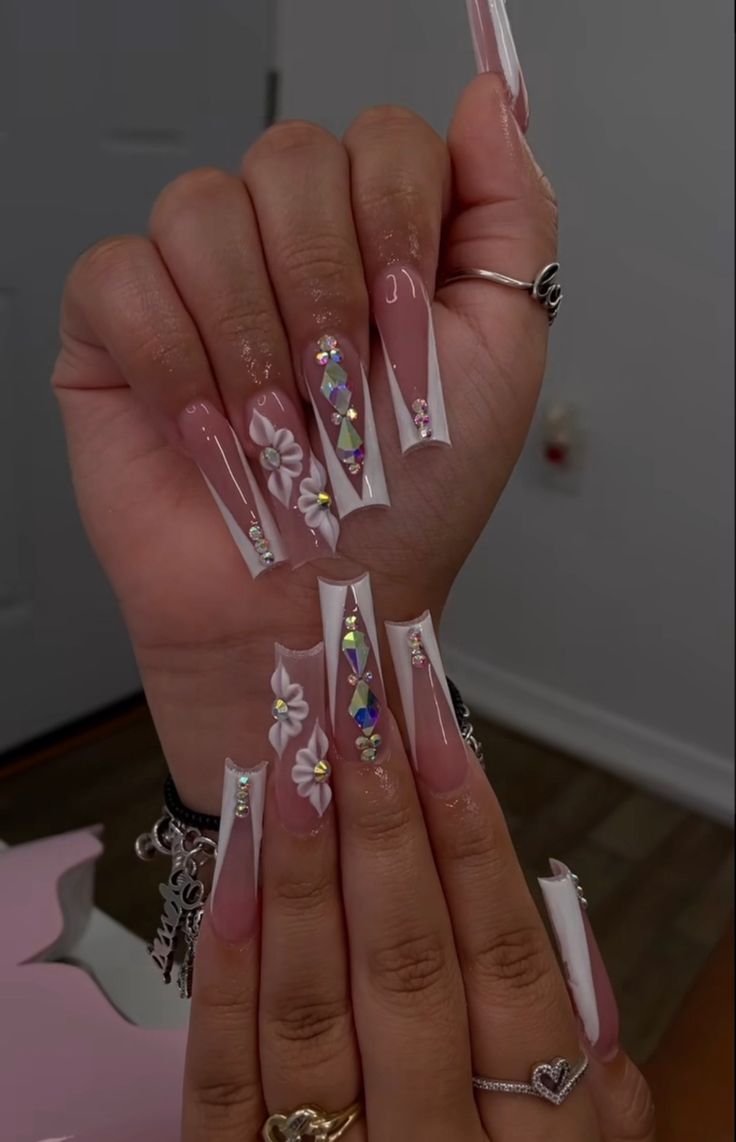 Chic Nail Design: Square Tips in Soft Pink and White with Floral Patterns and Rhinestone Accents.