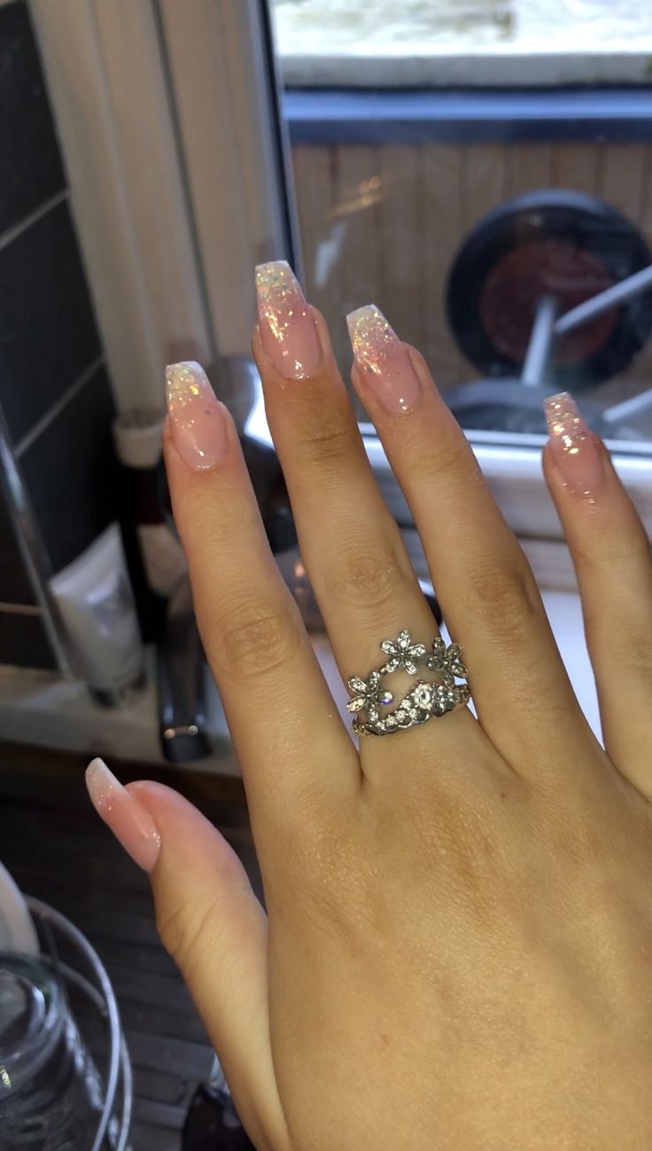 Sophisticated Pink Ombre Long Nails with Sparkling Tips and Elegant Ring Accent.