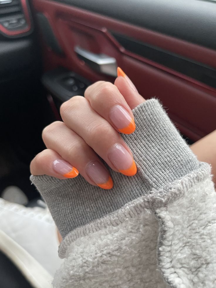 Chic French Manicure with Bold Orange Tips for a Fun and Modern Aesthetic.