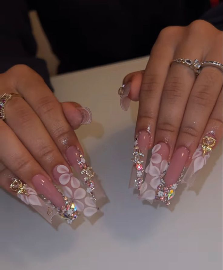 Elaborate Soft Pink Nail Design with Rhinestones and Floral Accents for Special Occasions.