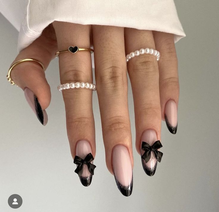 Sophisticated Ombre Nail Design with Charming Black Bows and Dainty Rings.