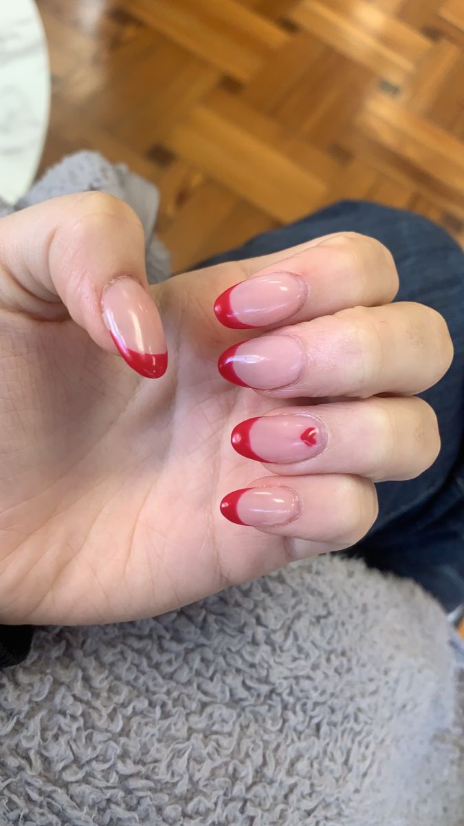 Chic Nude Nails with Vibrant Red Tips and Playful Heart Accent.