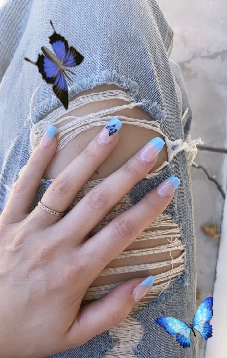 Delicate Light Blue Ombre Nail Design with Floral Accents and Whimsical Butterfly Embellishments.