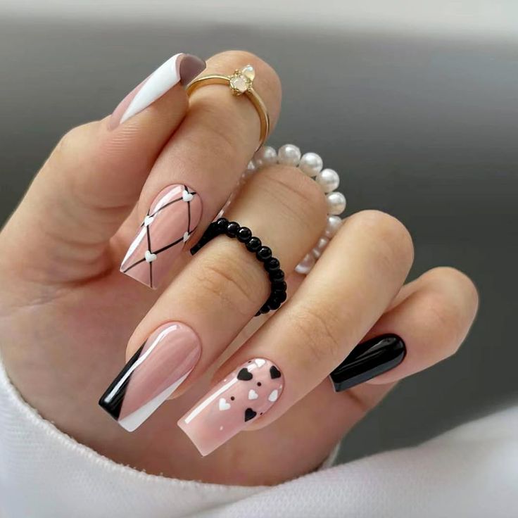 Chic and Playful Nail Design: Elegant Nude and Black with Heart Accents and Geometric Lines.