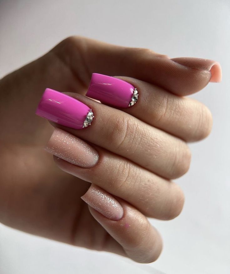 Elegant Nail Design: Vibrant Pink with Sparkling Rhinestones and Subtle Nude Shimmer.