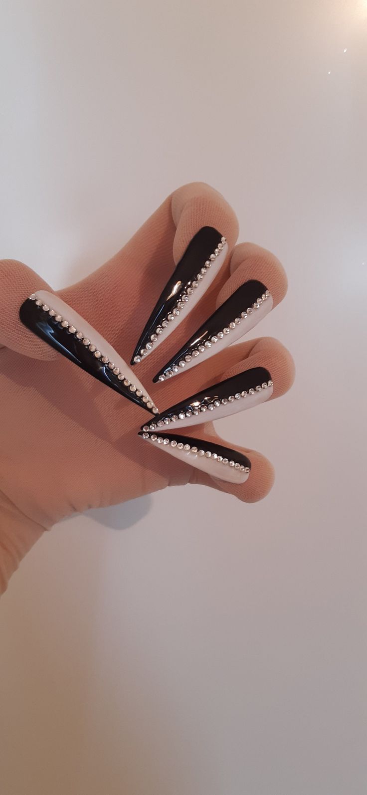 Elegant Black and White Stiletto Nails with Rhinestones: A Striking Glamorous Design.