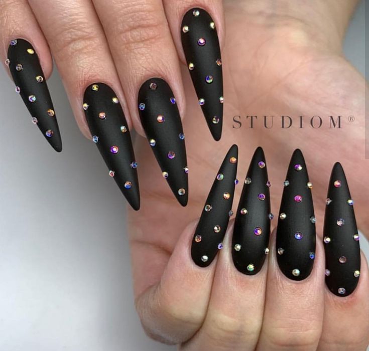 Bold Matte Black Stiletto Nails with Colorful Rhinestones for Glamorous Impact.