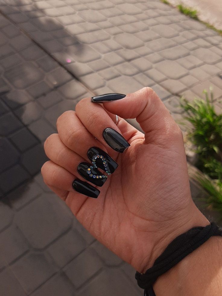 Chic Black Nail Design: Glossy Long Nails with Intricate Patterns and Colorful Rhinestones.