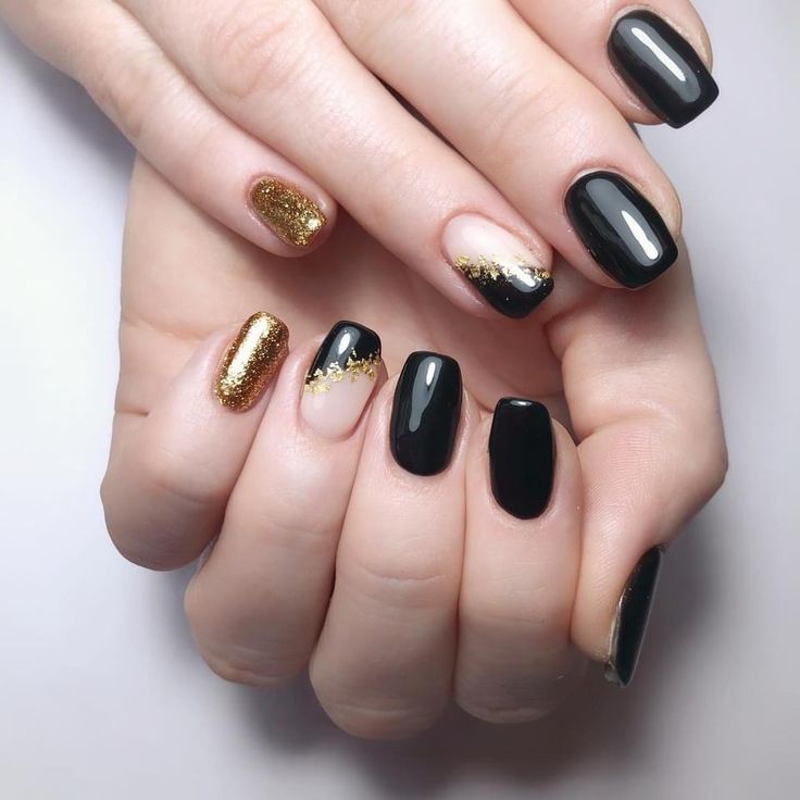 Elegant Black and Gold Nail Design with Glossy Accents and Glitter Details.