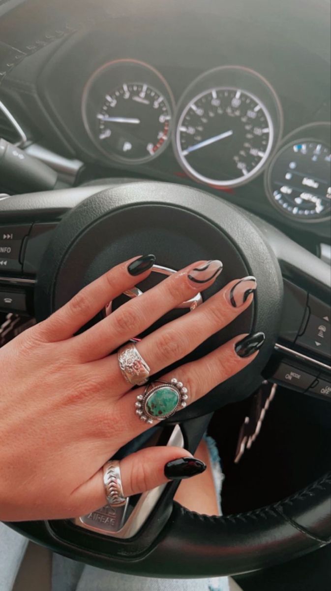 Bold Contrast: Stylish Black and Nude Manicure with Abstract Designs and Eye-Catching Rings.