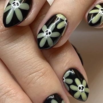 Edgy Floral Nail Art: Bold Black Background with Pale Green Flowers and Skulls.