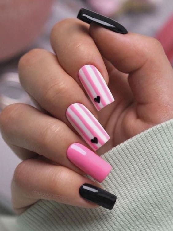 Unique Pastel Pink and Bold Black Nail Design with Playful Stripes and Heart Accents.