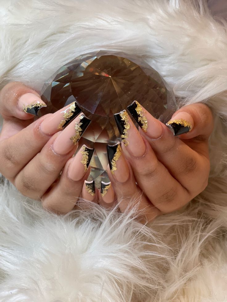 Sophisticated Elegant Nail Design: Nude, Black, and Gold Accents with Pointed Tips.