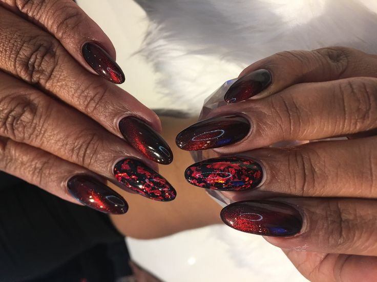 Chic Almond-Shaped Nails: Deep Red and Black Elegance with Glittery Abstract Patterns.