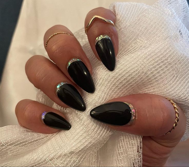 Chic Almond-Shaped Nails with Black Polish and Glamorous Gem Accents