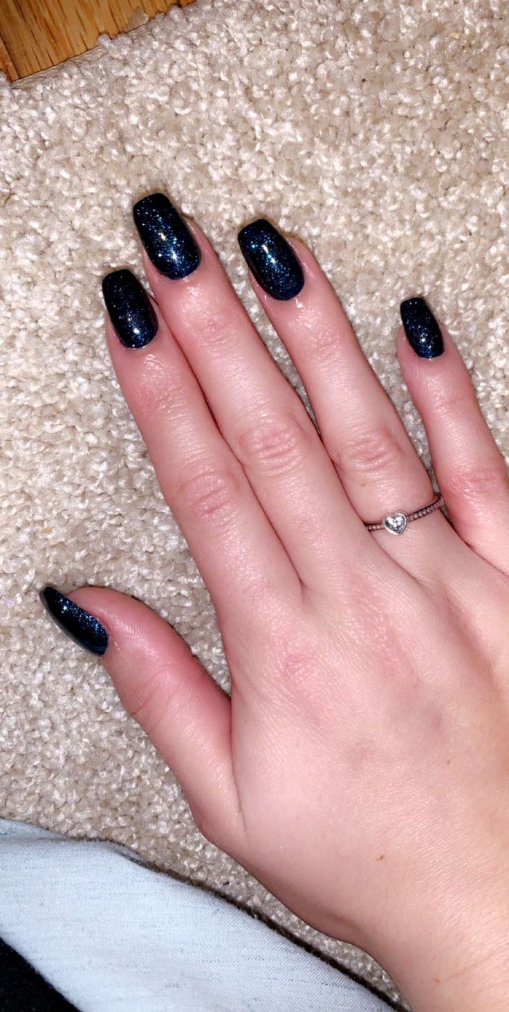 Sophisticated Deep Blue Glitter Manicure with Long Square Nails and Silver Ring Accent.