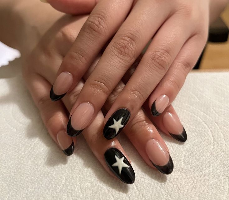 Chic Nude and Black Nail Design with Glossy Tips and Playful White Star Accent.