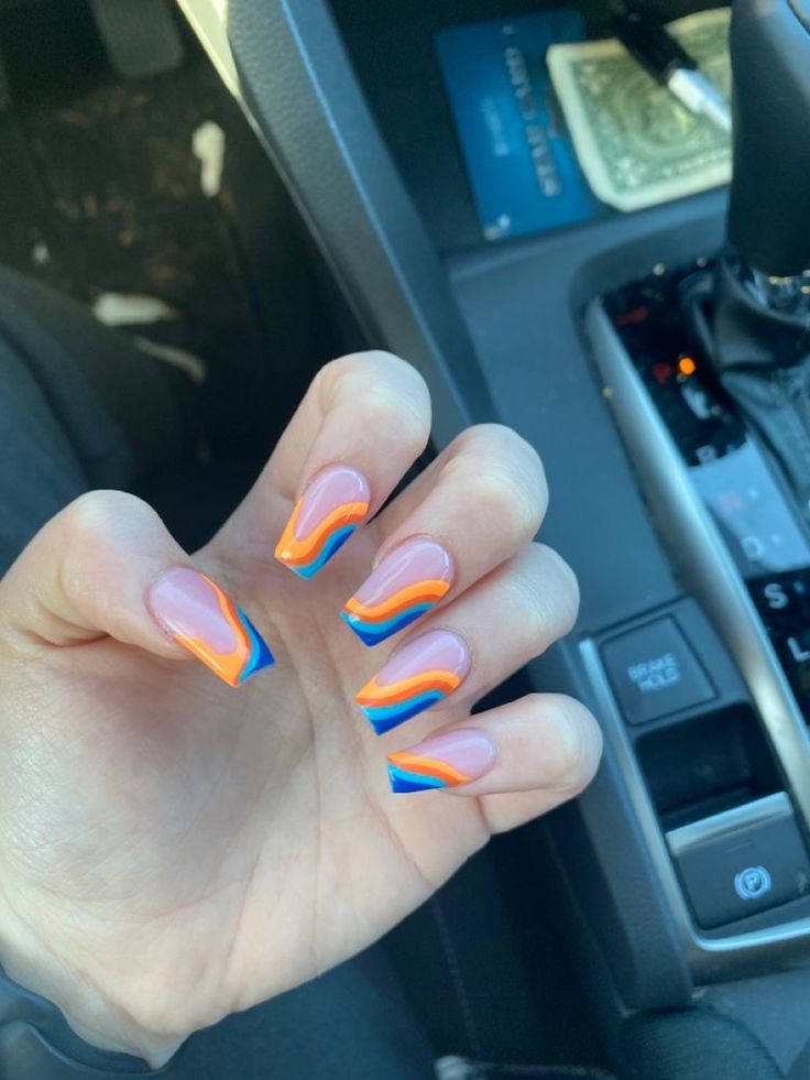 Dynamic Colorful Nail Design: Bright Orange and Blue Gradient with Bold Waves.