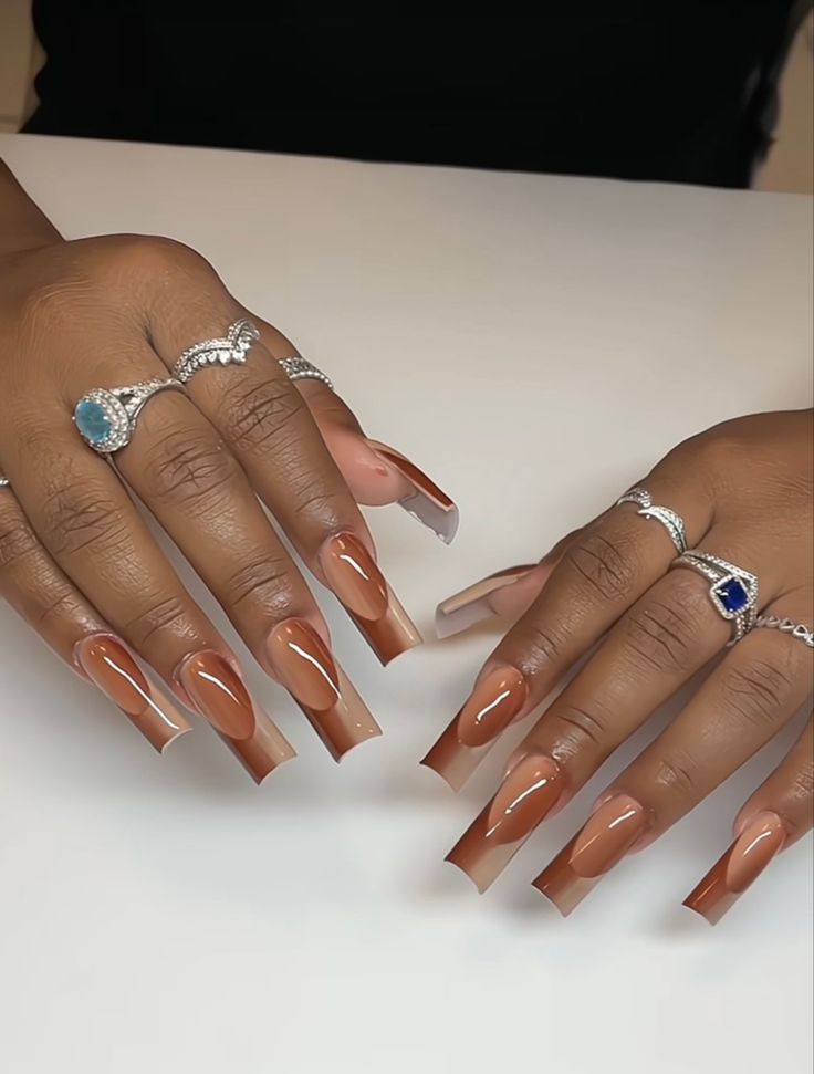 Elegant Almond-Shaped Gradient Nails: A Sophisticated Blend of Nude and Caramel with Glamorous Ring Accents.