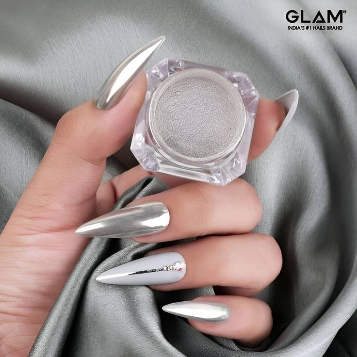 Glamorous Silver Nail Design with Elongated Tips and Elegant Embellishments.