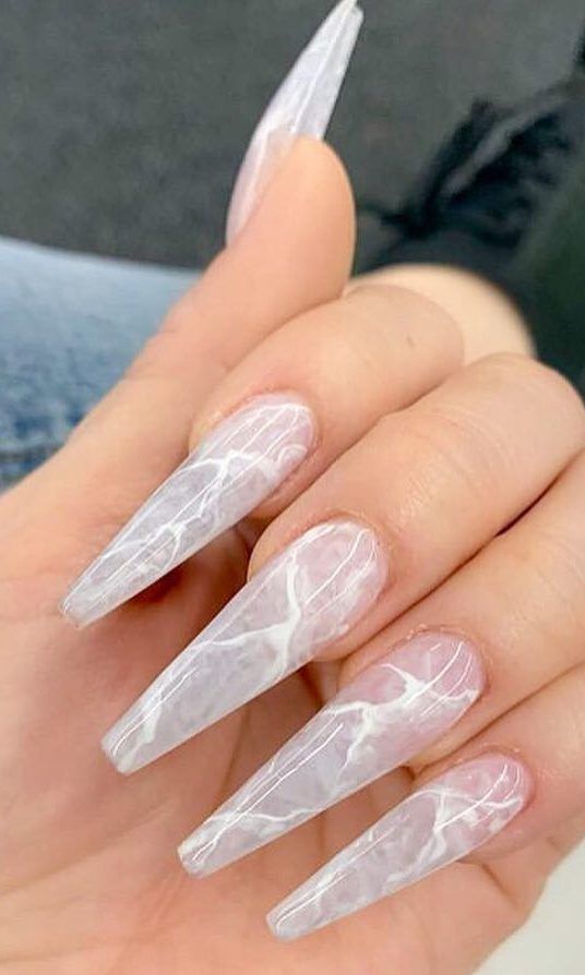 Elegant Translucent White Stiletto Nails with Marbled Patterns: A Stylish Blend of Simplicity and Artistry.