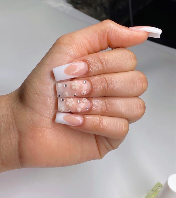 Elegant French Tip Nail Design with Floral Accents and Rhinestones