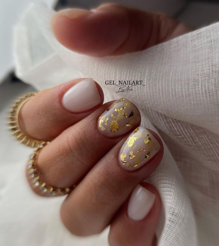 Sophisticated Nail Design: Soft Beige Base with Gold Foil and Modern White Accents.