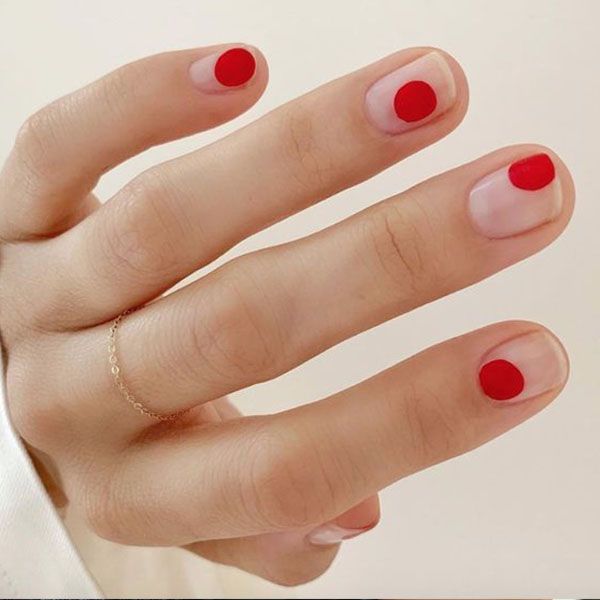 Chic Minimalist Nail Design: Clear Base with Bold Red Circular Accents.