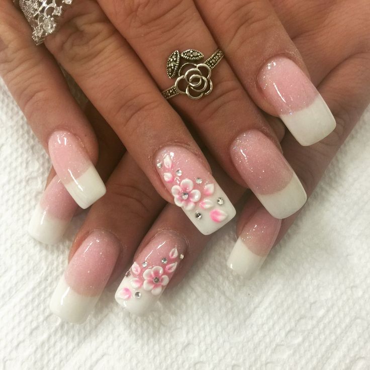 Chic Ombre Nails: Soft Pink Gradient and Floral Designs with Gem Accents.