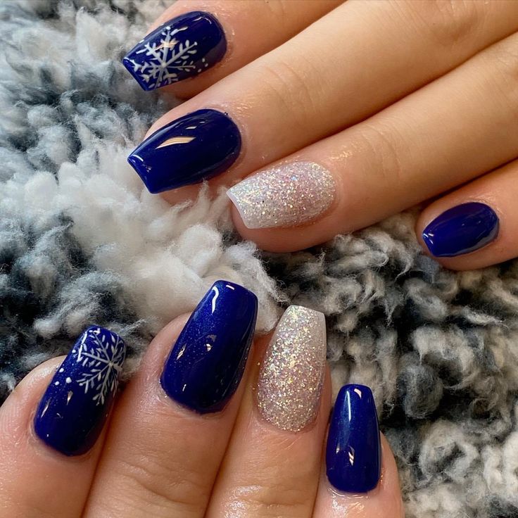 Chic Winter-Inspired Nail Design: Elegant Rich Blue Base with Sparkling Silver Accents and Snowflake Patterns.