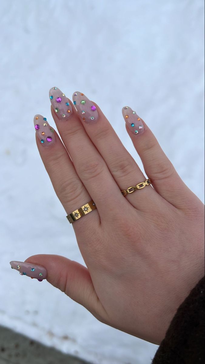 Whimsical Sparkling Nail Design with Colorful Gems and Elegant Gold Accents.