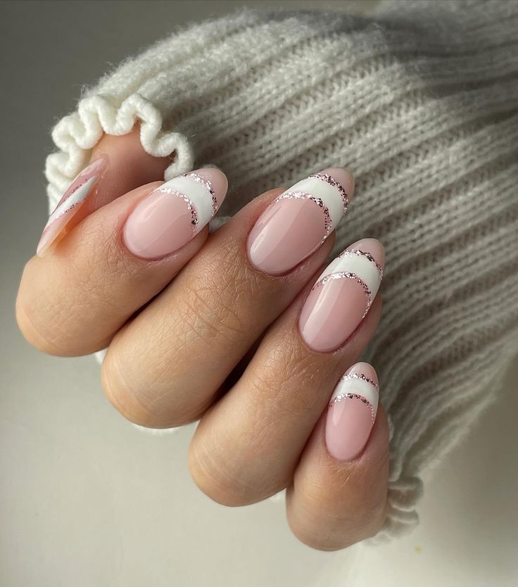 Chic Soft Pink Nail Design with Curved White Tips and Sparkling Glitter Accents.