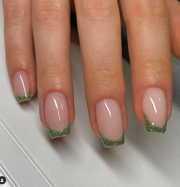 Chic Glossy Nude Nails with Sparkling Green Tips for a Modern Elegance.