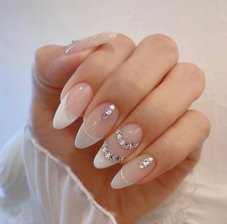 Chic Almond-Shaped French Tip Nails with Glossy Nude Polish and Rhinestones.