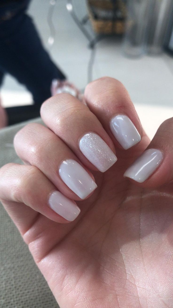 Elegant White Glossy Nail Design with Subtle Glitter Accents for Refined Aesthetics.