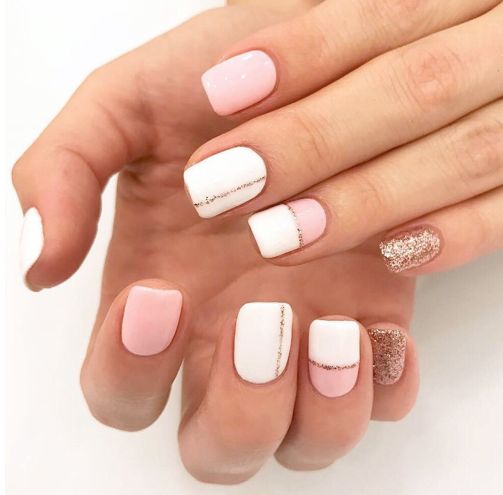 Chic Pastel Pink and White Nail Design with Elegant Geometric Patterns and Playful Glitter Accents.