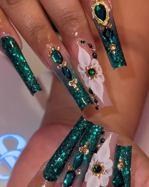 Luxurious Emerald Green Nails Adorned with Floral Motifs and Gemstones for Glamorous Occasions.