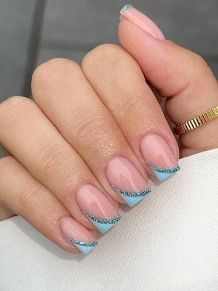 Chic Nude Nails with Delicate Blue Tips and Sparkling Accents.