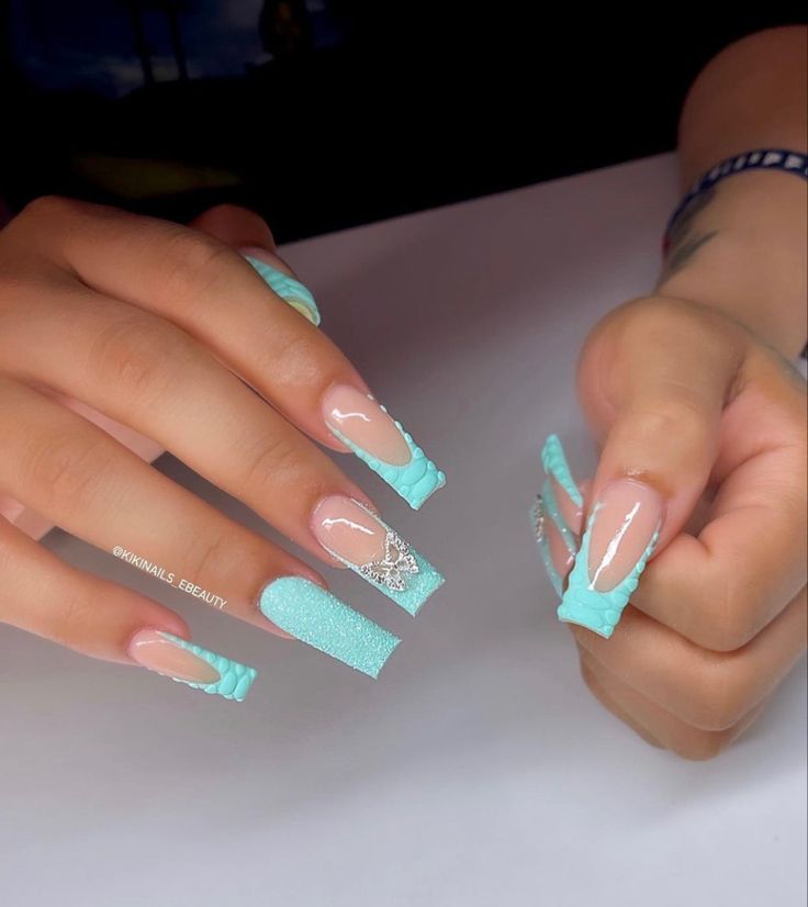 Vibrant Turquoise Nail Design: Glossy, Textured Finishes with Glitter and Intricate Art for a Bold Statement.