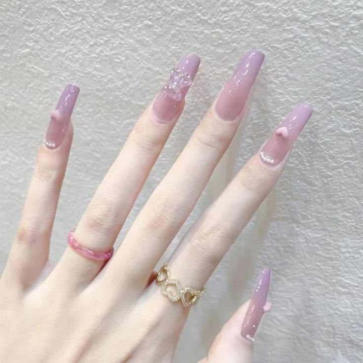 Chic Soft Pink Gradient Nails with Gem Accents and Elegant Ring Coordination.