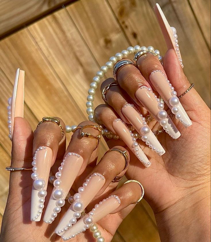 Luxurious Stiletto Nail Design with Soft Nude and Pearl Accents.