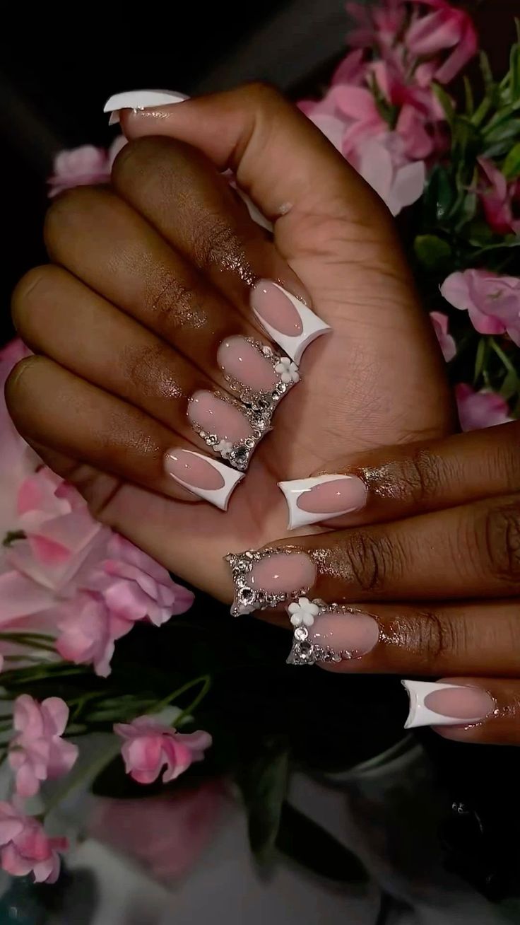 Chic Pink and White Nail Design with Gem Accents and Floral Backdrop