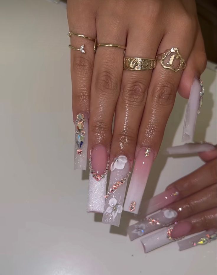 Sophisticated Long Nails: Glossy Pink-White Ombre with Floral Embellishments and Glamorous Rhinestones.