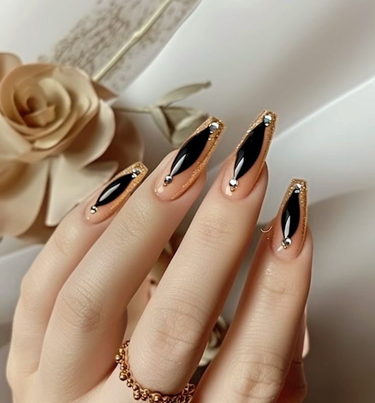 Chic Black and Gold Nail Design with Elongated Tips and Rhinestone Accents