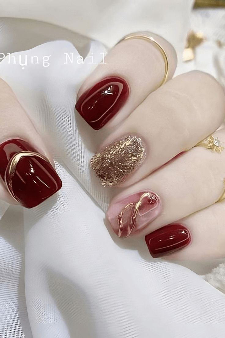 Chic Burgundy and Gold Nail Design with Artistic Swirls for Elegant Occasions.